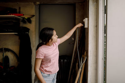 Girl plugging cable in electric socket at storage room