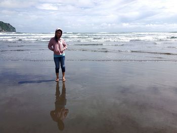 Woman standing on shore at beach against sky