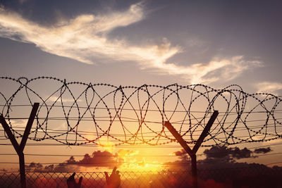 Silhouette fence against sky during sunset