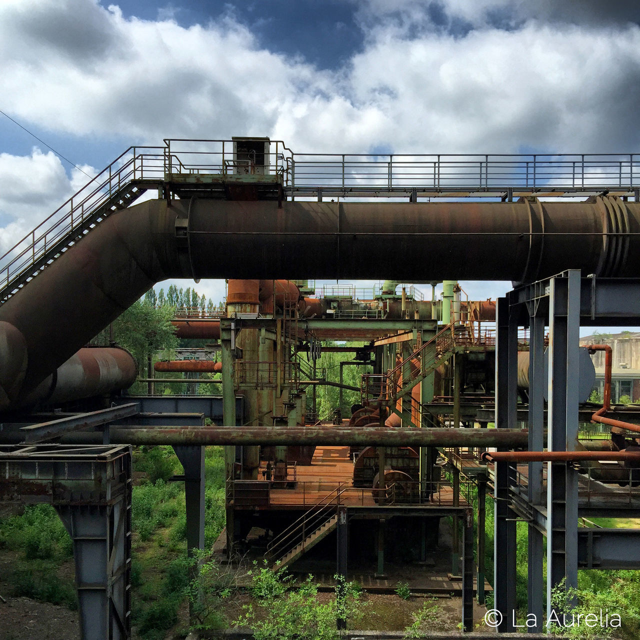 sky, cloud - sky, built structure, architecture, railing, cloudy, transportation, cloud, bridge - man made structure, connection, metal, day, engineering, low angle view, outdoors, rail transportation, train - vehicle, railroad track, travel, public transportation