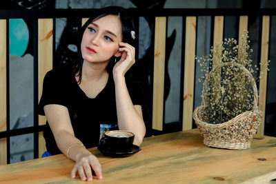 Young woman looking away while sitting on table