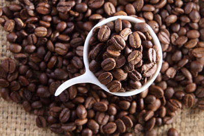 High angle view of cup on roasted coffee beans