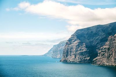 Scenic view of sea by mountains against sky