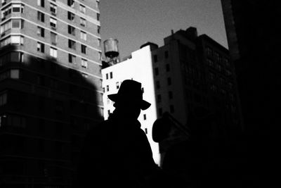Low angle view of silhouette statue against buildings in city