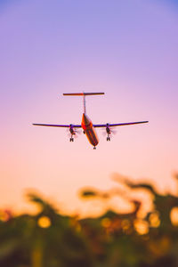 Low angle view of airplane flying against dramatic sky during sunset