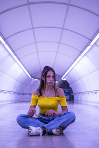 Full length of young woman sitting on floor in tunnel