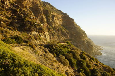 Scenic view of cliff by sea against clear sky