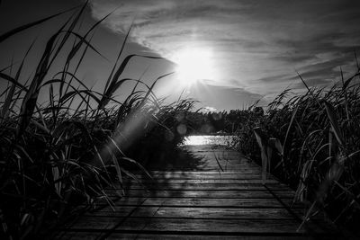 Walkway amidst water against sky