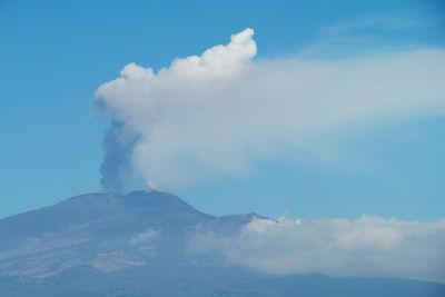 Low angle view of volcanic etna mountain against blue sky