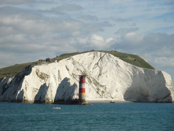 Lighthouse by sea against sky