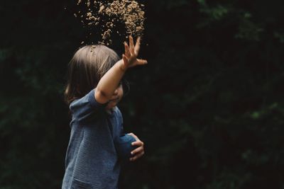 Close-up of girl standing against trees at night