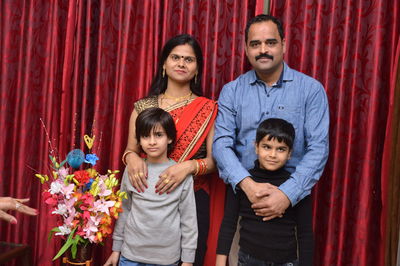 Portrait of happy family against curtain