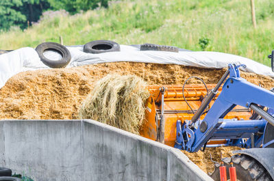 Earth mover carrying dry grass at farm