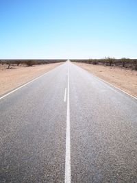 Empty road passing through landscape against clear sky