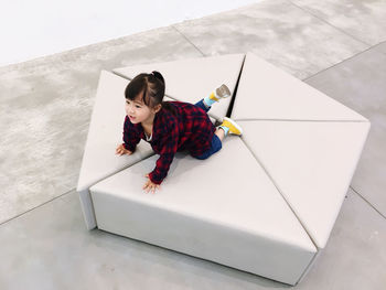 High angle view of girl kneeling on seat