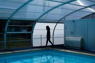 Side view of woman standing by swimming pool