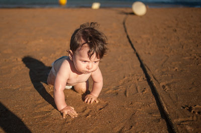 High angle view of shirtless boy on sand at beach