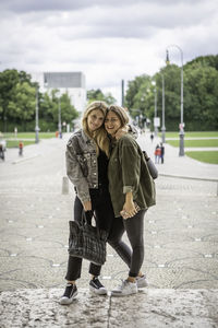 Portrait of happy female friends standing on street in city