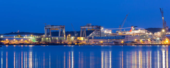 Illuminated commercial dock against clear blue sky at night