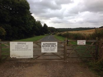 Information sign on field against sky