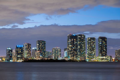 Illuminated buildings in city against sky at night