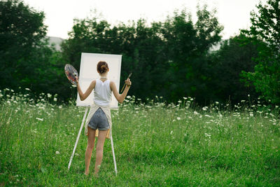 Woman holding umbrella standing on field