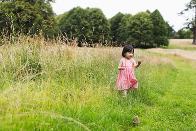 Full length of cute girl standing on grass outdoors