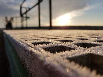 Close-up of snow on land against sky during sunset