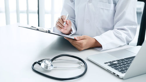 Midsection of man using laptop on table