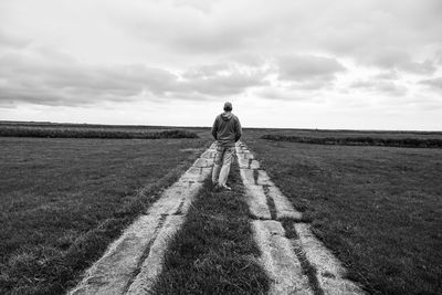 Rear view of man standing on field against sky