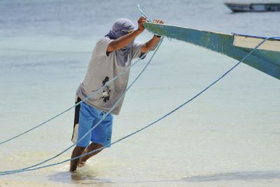 Fisherman pushing boat at sea shore