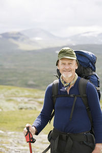 Portrait of confident hiker standing against mountains