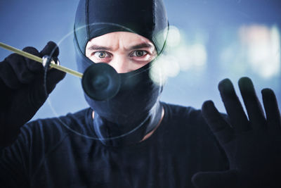 Close-up of burglar breaking glass window