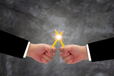 Midsection of man holding illuminated lighting equipment against bright sun