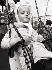 Close-up of boy sitting on swing at playground