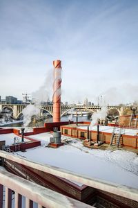 Snow covered factory against sky during winter