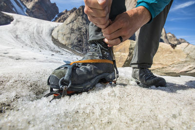 Detailed view of climber tightening his crampon before climbing.