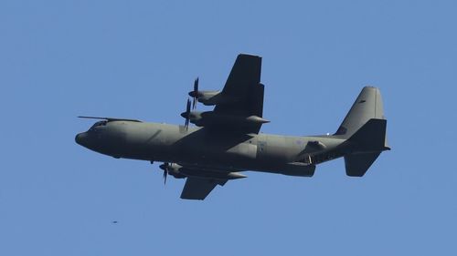 Low angle view of airplane flying against clear blue sky