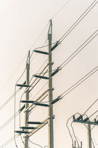 Low angle view of electricity pylon against clear sky