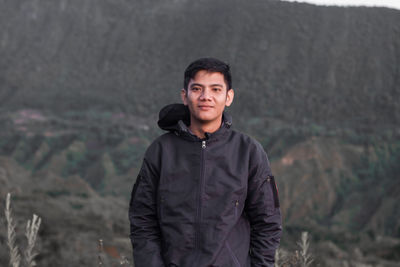 Portrait of young man standing against mountain