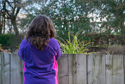 Rear view of woman standing against tree trunk