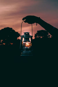 Silhouette of illuminated light bulb against sunset sky