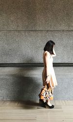 Side view of woman standing against wall