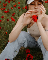 Low section of woman blowing bubbles while sitting on field