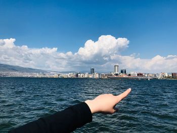Midsection of person against sea and cityscape against sky