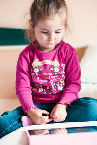 Cute girl watching video in digital tablet at home