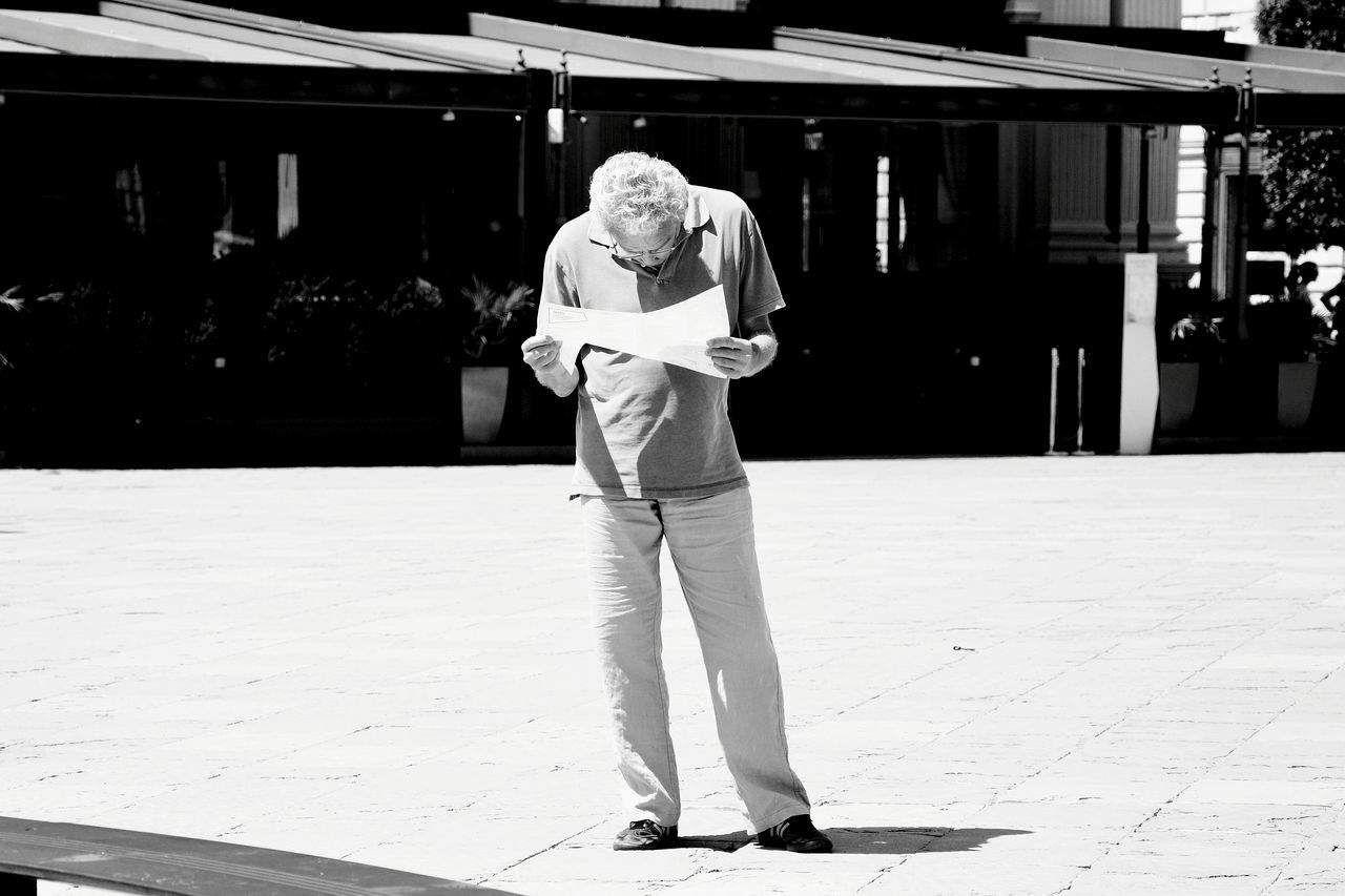 one person, full length, front view, real people, portrait, looking at camera, building exterior, casual clothing, lifestyles, standing, smiling, architecture, day, city, footpath, built structure, leisure activity, adult, men