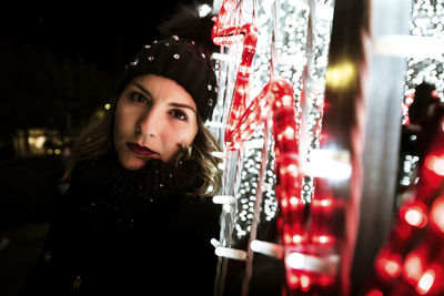 A young girl is posing and looking at the camera next to christmas lig