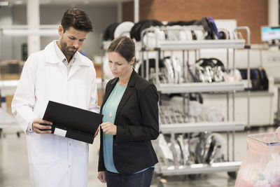 Businesswoman and engineer looking at file in manufacturing plant