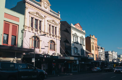 Cars on city street by buildings against sky